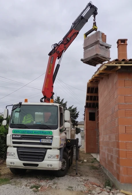 Camion grue livrant des matériaux de toiture près de Toulouse